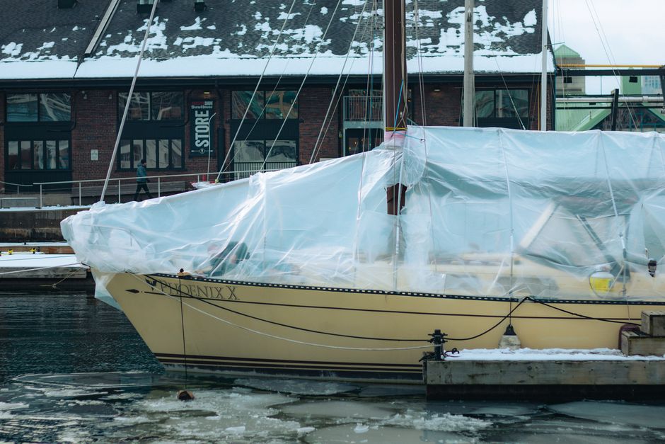 A covered yacht at a snowy dock in Toronto, showcasing winter boating preparations.